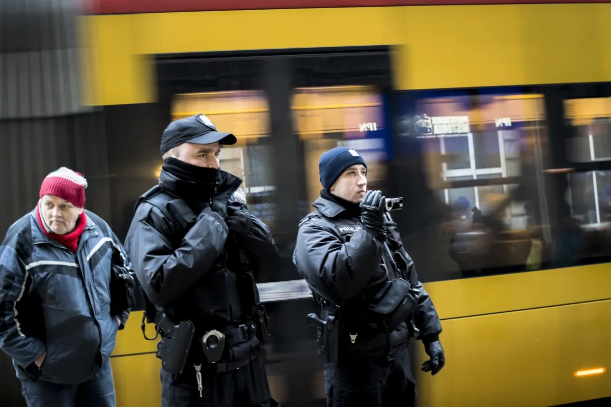 Armed police officers standing beside a yellow tram